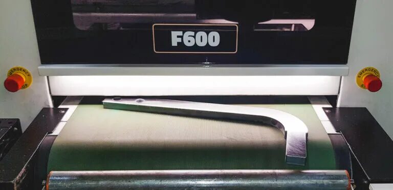 A finished stainless steel bracket on the Q-FIN F600's outfeed conveyor