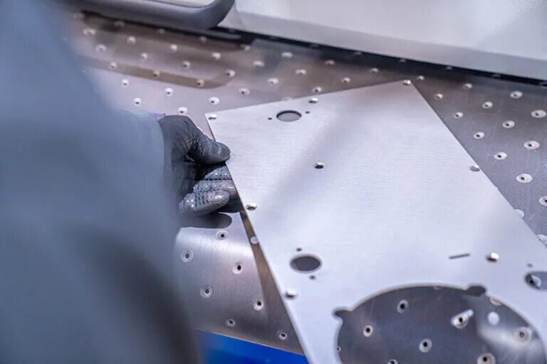Inspecting a laser-cut stainless steel panel on the cutting table